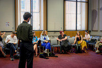 James Asfa standing and addressing a seated group in a semi-circle during the Community Partnerships Masterclass